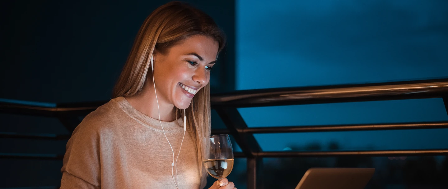 Frau schaut im dunkeln auf den beleuchten Display eines Laptops. Oben links wird das Mastercard Logo angezeigt.