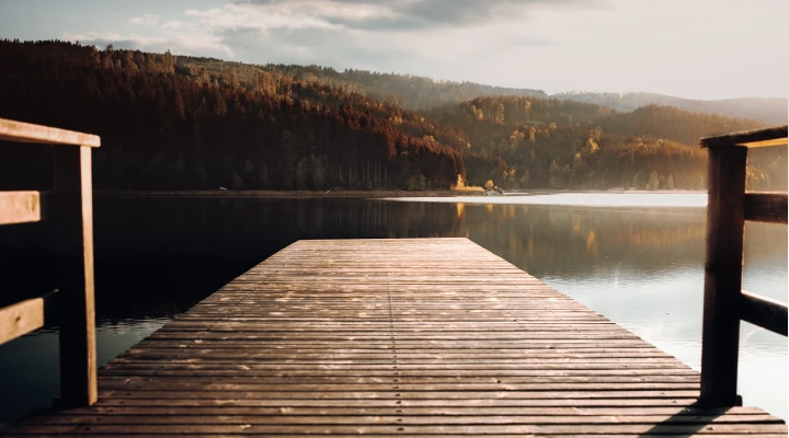 Steg führt auf einen See umringt von Bergen