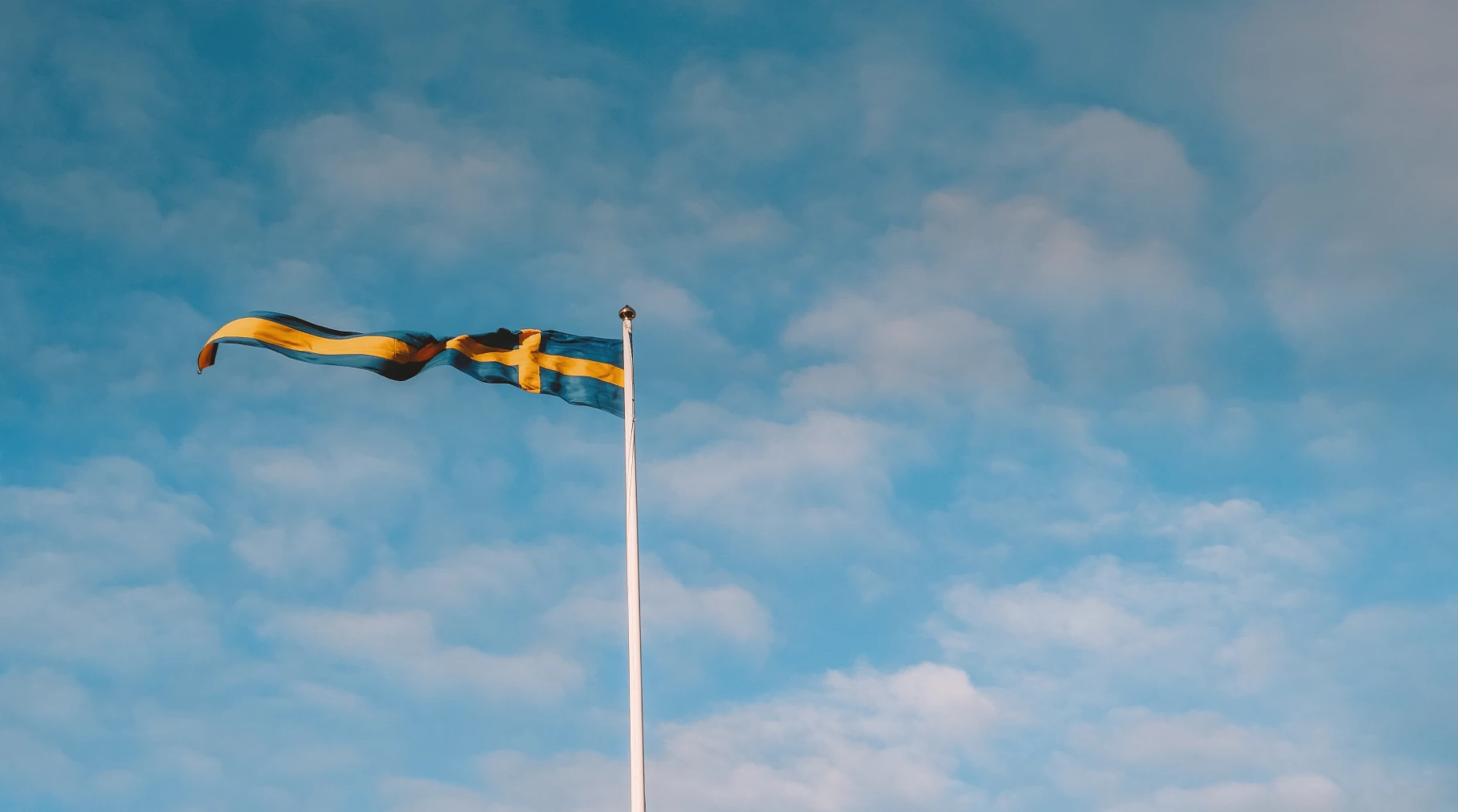 Blauer Himmel mit Wolken und schwedischer Flagge TF Bank