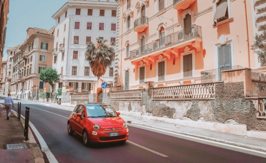 Ein kleines rotes Auto fährt auf einer Straße vor Gebäuden