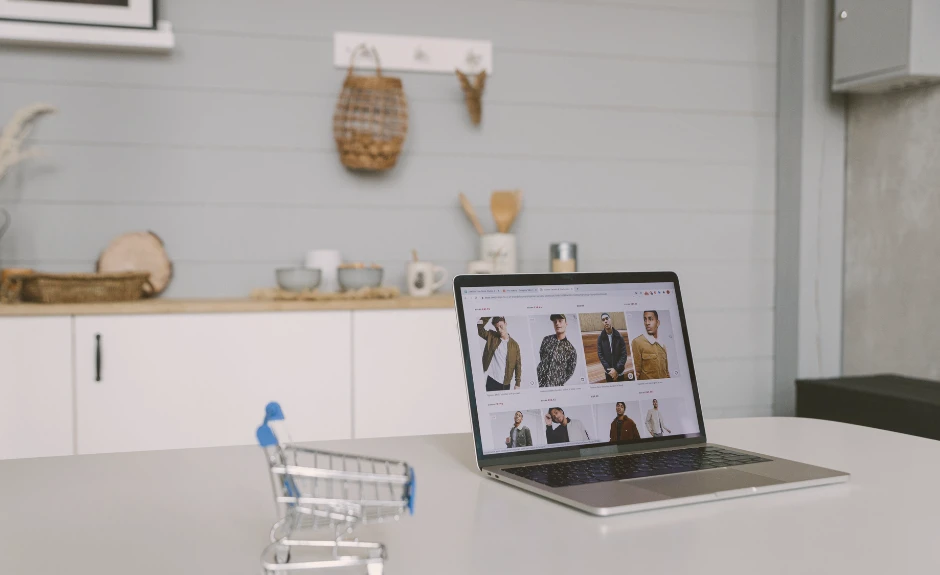 Eine moderne Wohnung mit einem kleinen Einkaufswagen, daneben ein Laptop, wo ein Online-Shop sichtbar ist