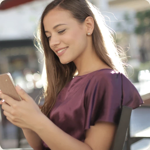 Frau schaut lächelnd auf ihr Handy.