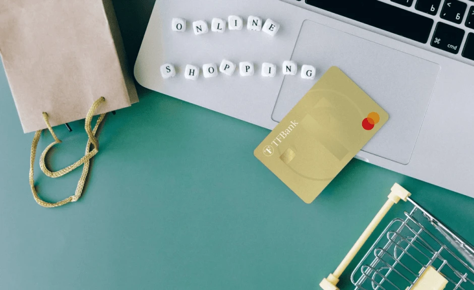 Die TF Mastercard Gold liegt auf einem Laptop, daneben der Schriftzug Online Shopping